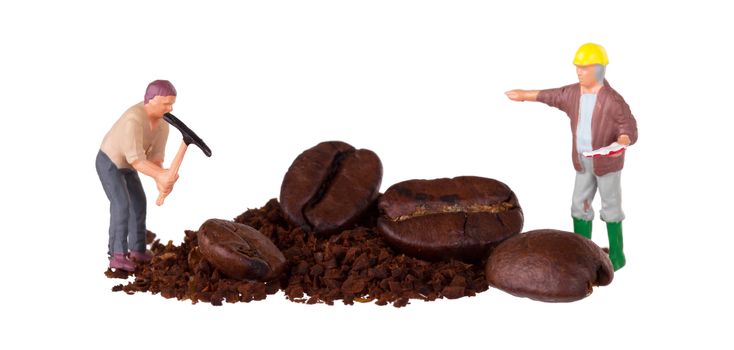 Miniature worker with pickaxe working on a coffee bean