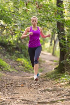 Pretty young girl runner in the forest.  Running woman. Female Runner Jogging during Outdoor Workout in a Nature. Beautiful fit Girl. Fitness model outdoors. Weight Loss. Healthy lifestyle. 