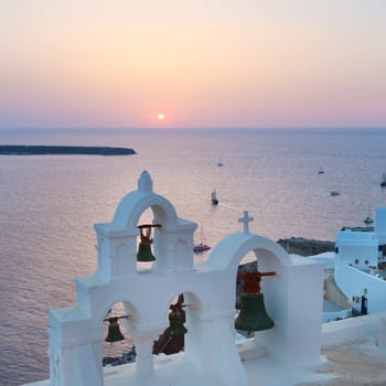 World famous traditional whitewashed chuche of Oia village on Santorini island, Greece. Sunset light.