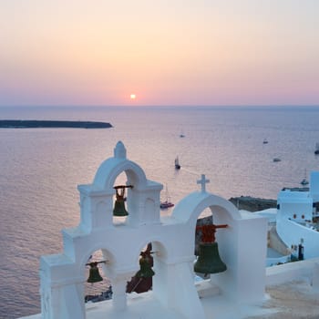 World famous traditional whitewashed chuche of Oia village on Santorini island, Greece. Sunset light.