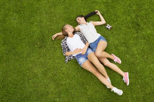 Female best Friends lying on the grass and having a good time together