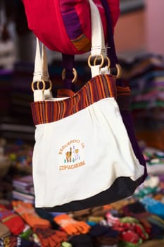 COPACABANA, BOLIVIA - OCTOBER 23, 2014: A handbag with the writing Recuerdo de Copacabana (Souvenir from Copacabana) hanging at a souvenir and handicraft stand in the small tourist town on the shore of the Titicaca Lake on October 23, 2014 in Copacabana, Bolivia