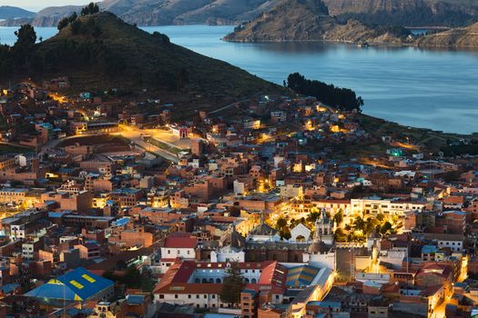 COPACABANA, BOLIVIA - OCTOBER 24, 2014: View shortly after sunset over the small touristy town of Copacabana and Lake Titicaca photographed from Kesanani hill on October 24, 2014 in Copacabana, Bolivia. In the lower part of the image the Basilica of Our Lady of Copacabana is visible. 