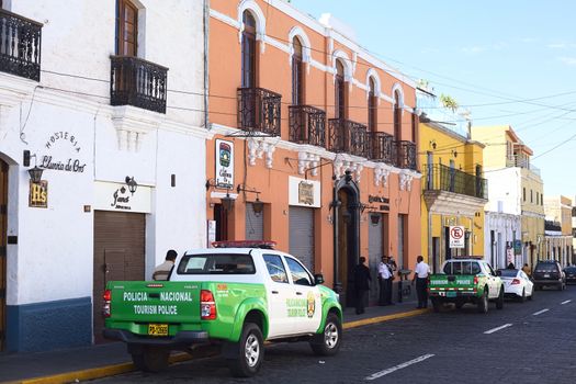 AREQUIPA, PERU - SEPTEMBER 9, 2014: Unidentified people on Jerusalen street with two tourism police pickups standing on the roadside on September 9, 2014 in Arequipa, Peru. Jerusalen street is in the city center and many hostels are located along it. 