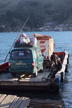 TIQUINA, BOLIVIA - OCTOBER 16, 2014: Wooden ferry loaded with truck, minibus and motorbike leaving one side of the Strait of Tiquina at Lake Titicaca on October 16, 2014 in San Pablo de Tiquina, Bolivia