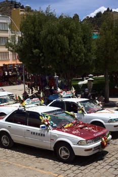 COPACABANA, BOLIVIA - OCTOBER 20, 2014: Decorated taxis standing in line for the blessing in front of the basilica on October 20, 2014 in the small tourist town of Copacabana, Bolivia. Daily many cars, buses and trucks receive blessing from the priest.  