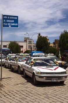 COPACABANA, BOLIVIA - OCTOBER 20, 2014: Decorated taxis standing in line for the blessing in front of the basilica on 6 de Agosto Avenue on October 20, 2014 in the small tourist town of Copacabana, Bolivia. Daily many cars, buses and trucks receive blessing from the local priest.  