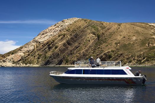ISLA DEL SOL, BOLIVIA - NOVEMBER 6, 2014: Unidentified people sitting on the roof of a tour boat leaving the Isla del Sol (Island of the Sun) on November 6, 2014 at Isla del Sol, Bolivia. Isla del Sol is a popular tourist destination in Lake Titicaca.  