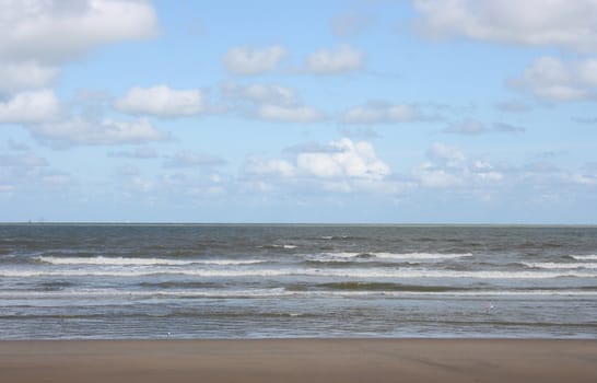 Waves with white crests inundate the sandy beach