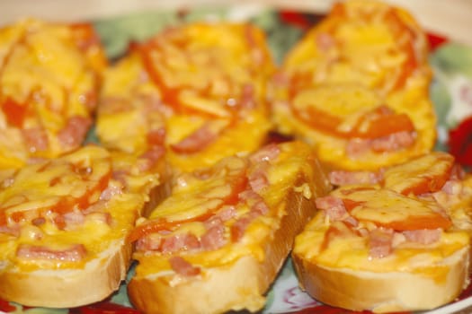 Hot sandwiches with smoked sausage and melted cheese on the plate