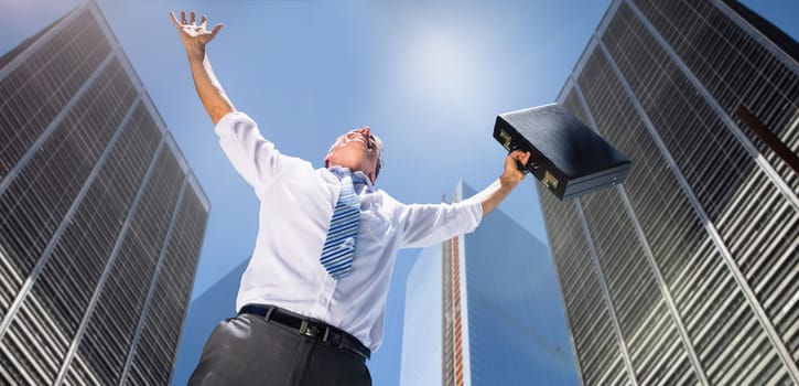 Composite image of businessman holding briefcase and cheering against skyscrapers