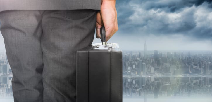 Businessman holding briefcase against room with large window looking on city