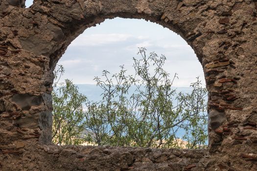 Ancient stone window that shows part of landscape
