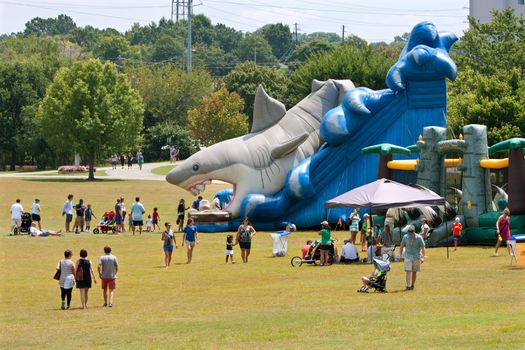 Atlanta, GA, USA - August 16, 2014:  Families walk to and from a giant inflatables playground in a field at the Piedemont Park Arts Festival. 