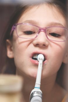 Girl brushing her teeth with an electric brush