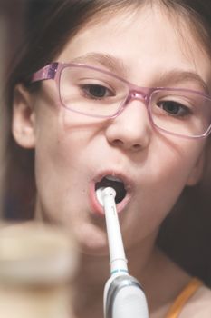 Girl brushing her teeth with an electric brush