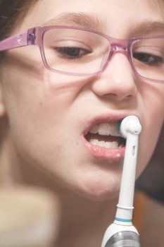 Girl brushing her teeth with an electric brush