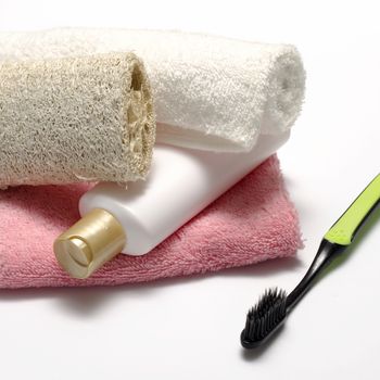 towel loofah liquid soap and toothbrush on a white background