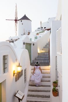 Runaway bride ona a staircase among traditional whitewashed  houses of Oia village on Santorini island, Greece.