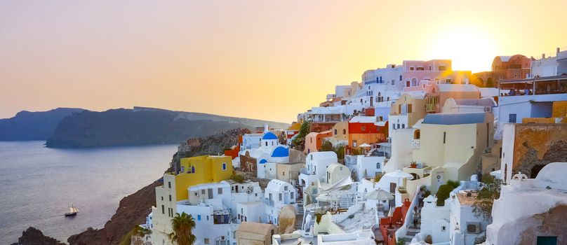 World famous traditional whitewashed chuches and houses of Oia village on Santorini island, Greece. Sunset.