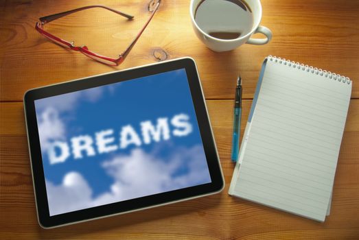 Computer tablet on a work desk with dreams cloud 