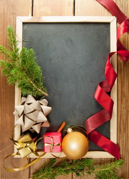 Blackboard with space surrounded by christmas decorations over wood