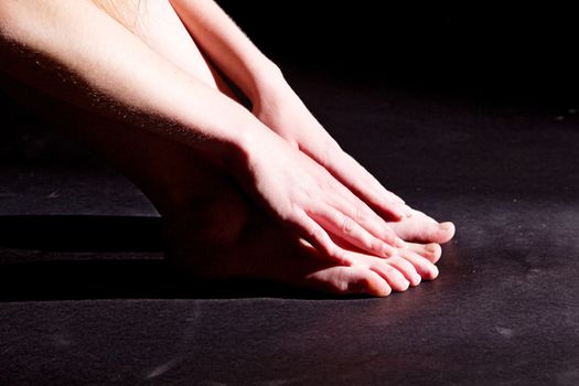 Photo shows a woman lighted and shadowed on the black background.