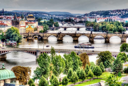 Photo shows the bridge, river and some old houses in Prague.