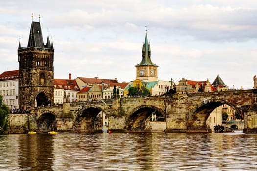 Photo shows the bridge, river and some old houses in Prague.