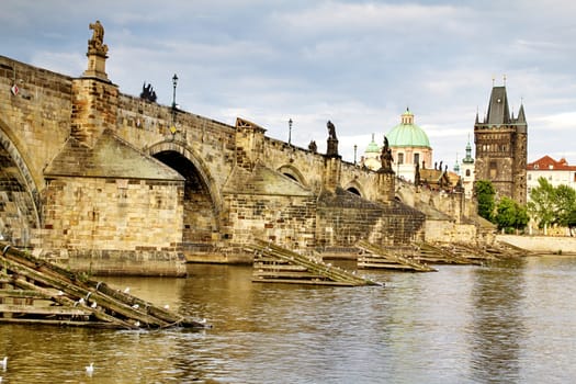 Photo shows the bridge, river and some old houses in Prague.