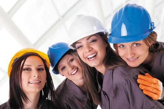 Young female construction workers with protective clothes and helmets. Isolated with work path.