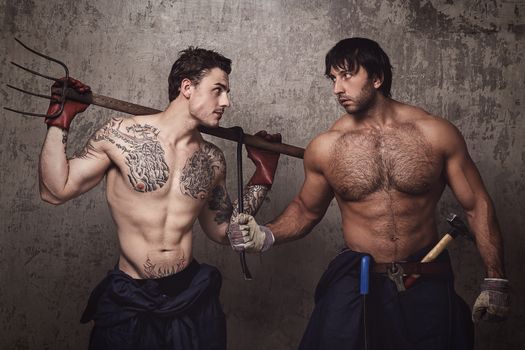 Strong and tattooed men with pitchfork