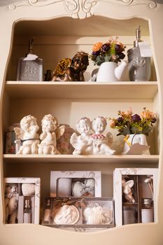 The wooden shelf with sculptures of white porcelain angels