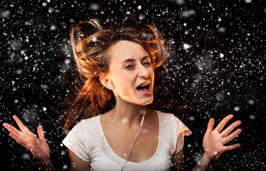 Beautiful woman listening to music during a snowfall