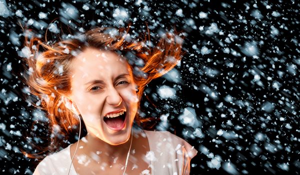 Beautiful woman listening to music during a snowfall