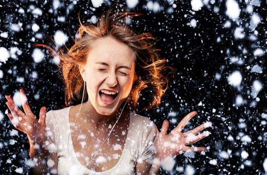 Beautiful Woman Listening Music and screams on a snowfall background