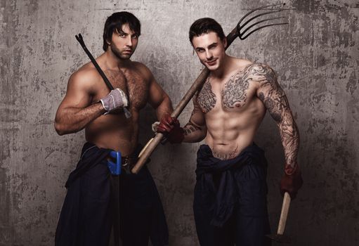 Strong and tattooed men with pitchfork