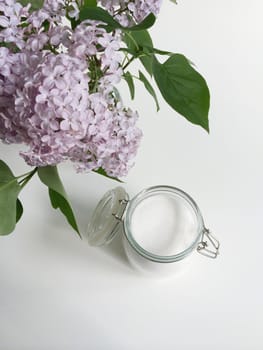 Glass jar of granulated white sugar and lilac flowers