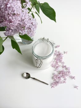 Glass jar of granulated white sugar and lilac flowers