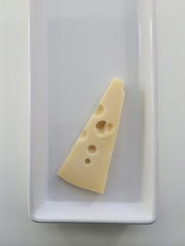 Slice of cheese with holes on a plate