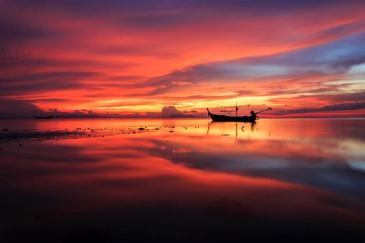 Silhouettes of longtail boat and sunrise in Phuket, Thailand