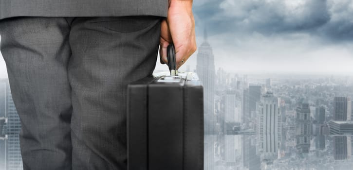 Businessman holding briefcase against room with large window looking on city