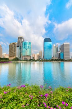 Modern city skyline of business district downtown with pink flowers and lake in front in day under blue sky
