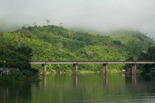 Bridge across river with mountain and fog