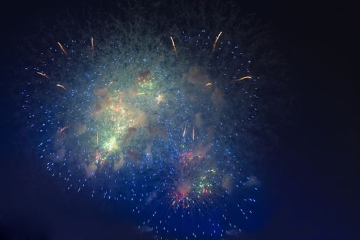 Fireworks in night dark sky with smoke after explosions