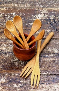 Arrangement of Small Wooden Spoons in Pot and Wooden Forks isolated on Rustic Wooden background