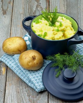 Delicious Homemade Mashed Potato with Dill and Spring Onion in Dark Blue Casserole with Lid on Rustic Wooden background