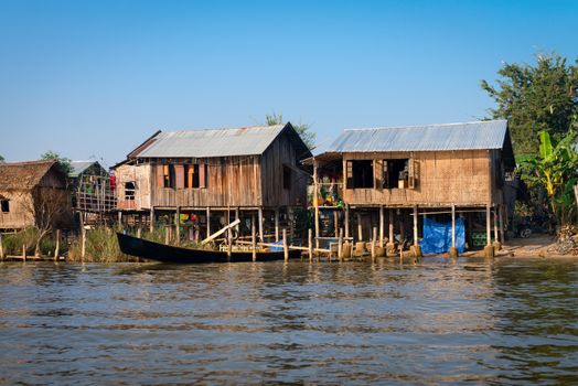 Traditional stilts wooden and bamboo houses and long boats of Intha people in water on Inle lake, Myanmar (Burma) 