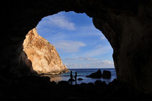 Lovely couple looking at each other in the cave in front of the Mediterranean sea
