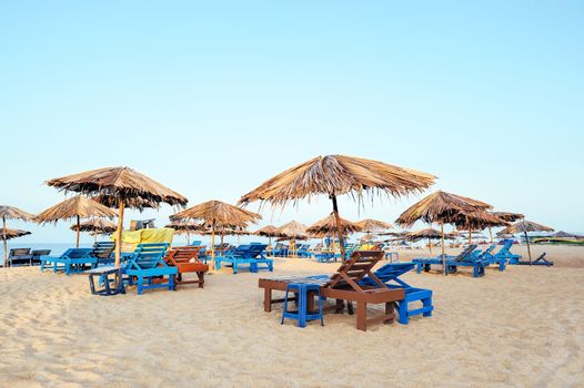 Beach umbrellas and deckchair on the tropical coast in Goa, india